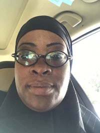 a woman wearing a hijab and glasses in a car