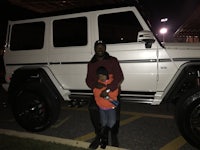 a man and a child standing in front of a white suv